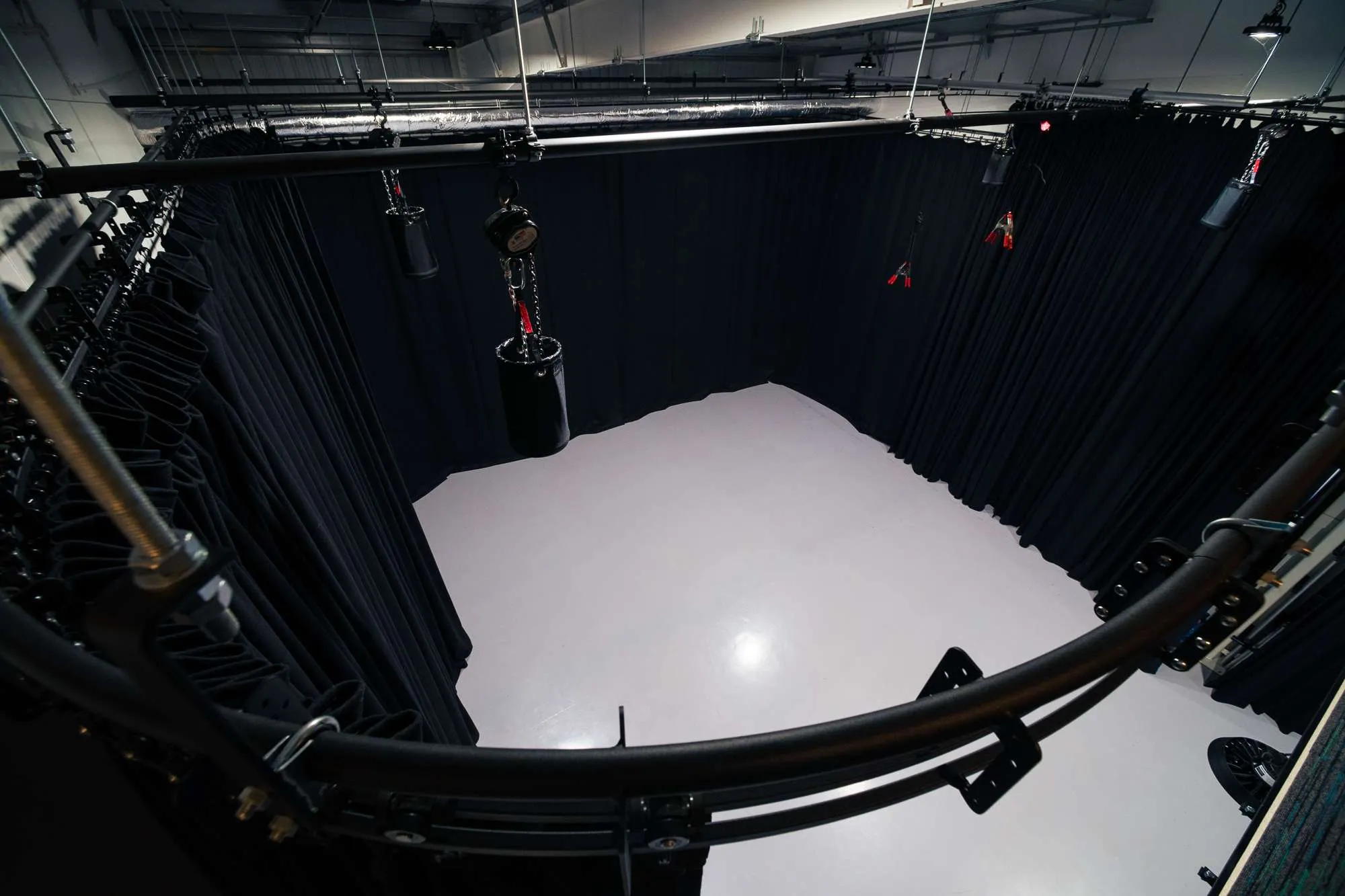 Doughty 6 track in a film studio. A spacious, empty film TV studio with a smooth, light gray floor, surrounded by black curtains and overhead stage lighting, giving the appearance of a photography or production space.